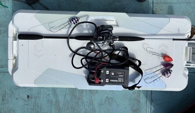 クーラーのふたに並べた竿、電動リール、バッテリーとタチウオテンヤ